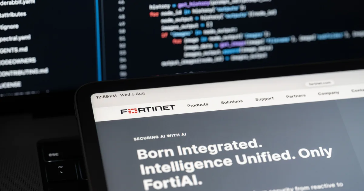 Tablet mit geöffneter Fortinet-Website vor einem unscharfen Monitor mit Quellcode